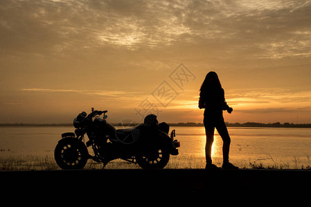 美丽的女人骑自行车享受日落图片