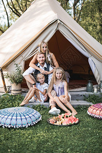 一家人在夏日旅行中坐在大棚屋帐篷附近图片