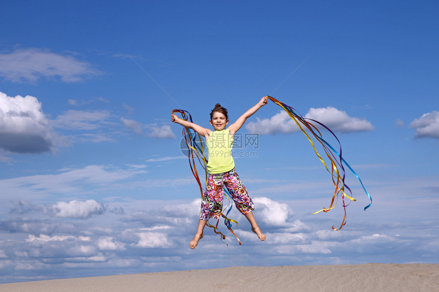 快乐的小女孩在沙滩上跳跃图片