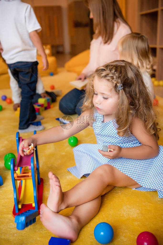 穿着衣服坐在地毯上玩具的可爱孩子在幼图片