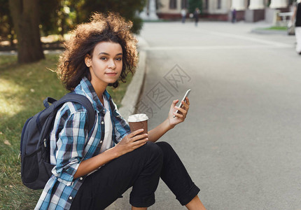 快乐的非洲裔美国学生女孩在大学背景下通过手机发送消息图片