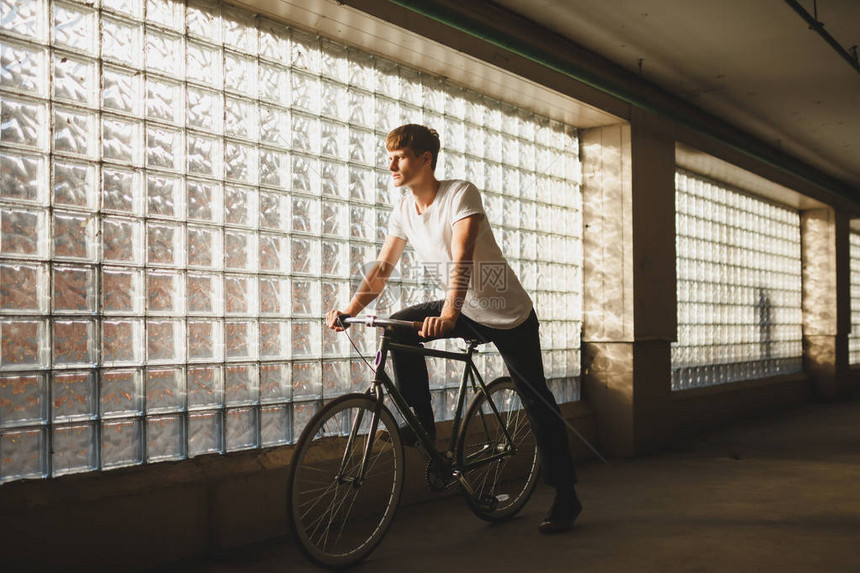 酷男孩骑着经典自行车梦幻般地看着一旁的画像身穿白色T恤的年轻体贴男子站在自行车上图片