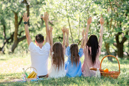 青年家庭在公园野餐时坐在草地上图片