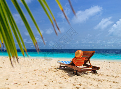 热带沙滩躺椅上的草帽和包图片