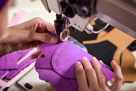 一名年轻女在缝纫机上缝了真正的儿童皮鞋的紫色单式缝纫机缝衣图片