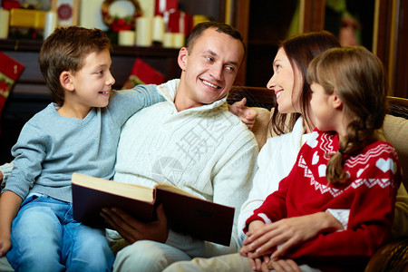 圣诞节晚间友善家庭阅读书的肖像图片
