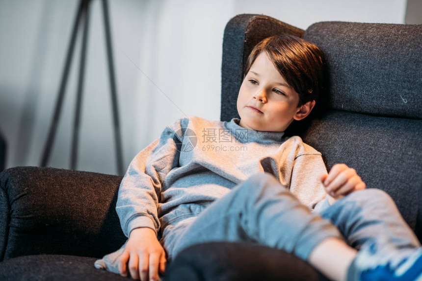 可爱的柔软小男孩坐在扶手椅上看图片