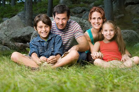 一家人坐在森林里的草地上图片