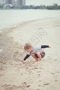 沙海湖洋河海滩上的一个小孩蹒跚学步的男孩寻找有趣的东西背景图片