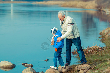 爷和孙子正试图在石头上过河图片