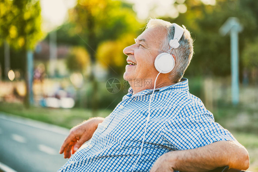 在耳机上监听音乐的老年图片