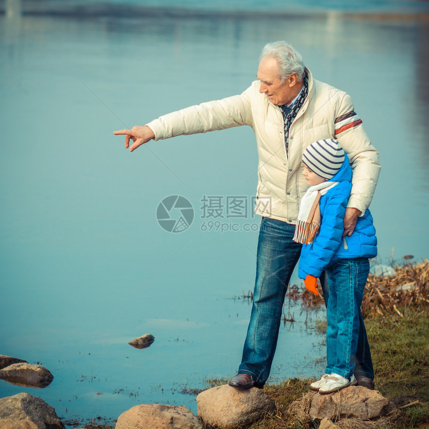 爷和孙子正试图在石头上过河图片