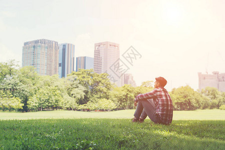 坐在公园的草地上独自与城市和天空对峙图片