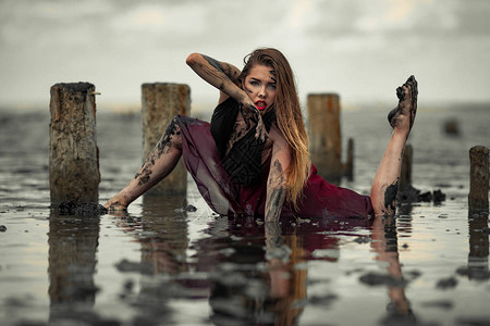 穿着红裙子的年轻泥巴女人在泥滩河口水中跳舞图片