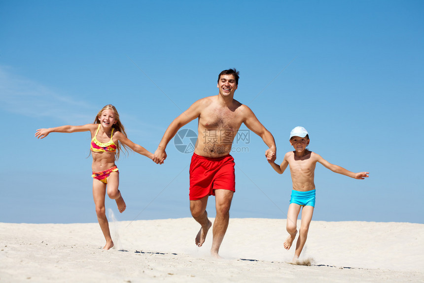 幸福一家人暑假在沙滩上奔跑的照片图片