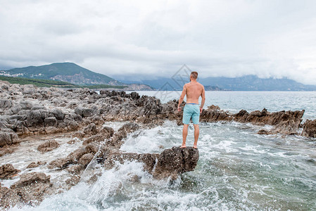 站在岩石海滩的英俊肌肉年轻男子看着蒙坦格罗高美图片
