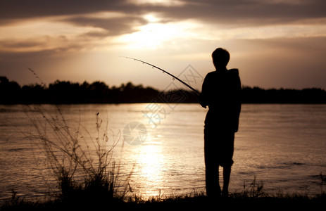 在日落时那个拿着钓鱼钩的家伙的背景图片