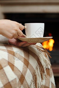 在壁炉旁喝茶的女人图片