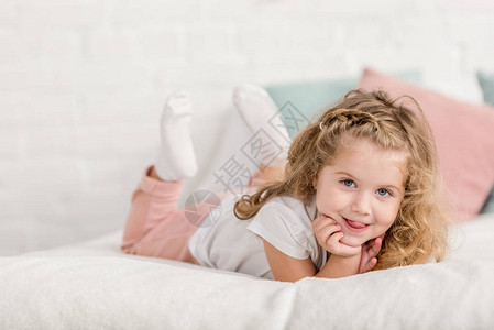 笑着可爱的快乐孩子躺在儿童室的床上图片