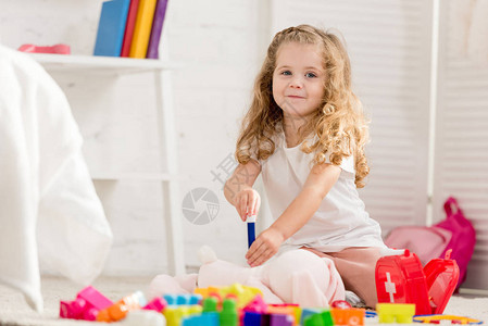 可爱的小孩检查兔子玩具在儿童室和看相机图片