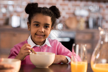 在家吃早餐的微笑小女孩的肖像图片
