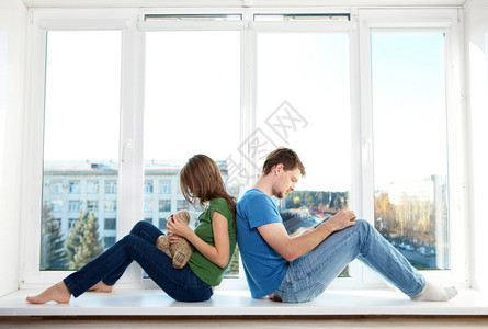 男人和女人背靠坐在窗台上的照片图片
