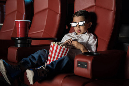 坐在电影院里的小男孩戴着3D眼镜看图片