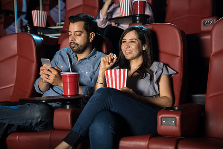 年轻男人和一个女人坐在电影院里时图片