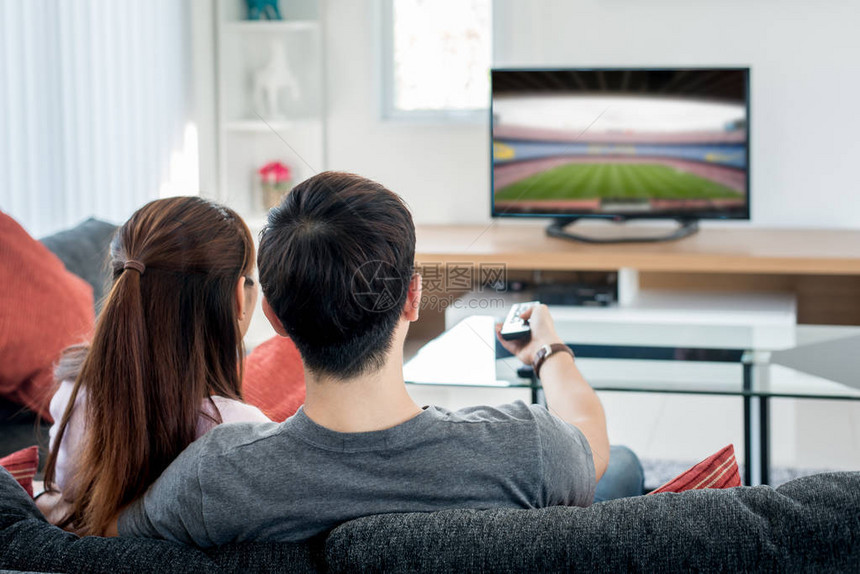 在客厅的电视上观看橄榄球足球节的概念图片