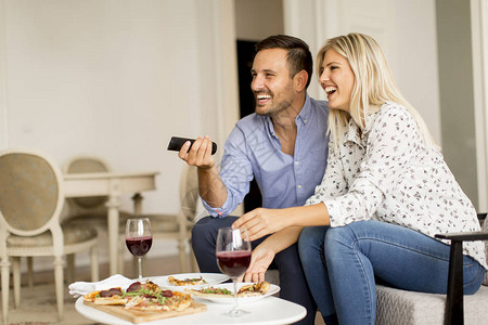 在家吃披萨和看电视的年轻夫妇图片