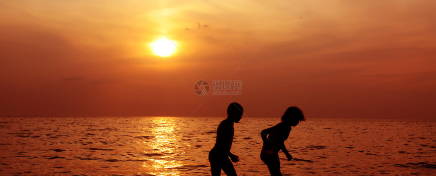 在海面和日落的背景下两个孩图片