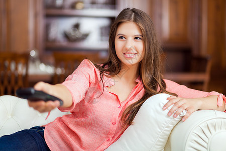 坐在沙发上看电视的年轻女人图片