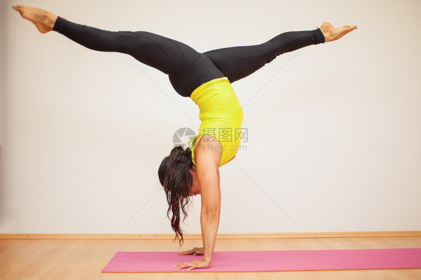 一个强壮的年轻女子在瑜伽工作室做头部腿分图片
