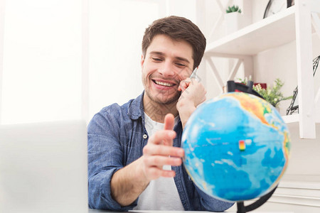 年轻快乐的人在家里玩地球仪和打电话图片