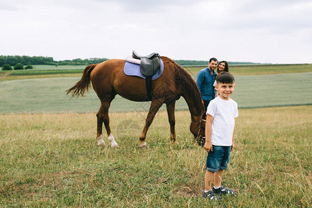 站在马旁边的家长们微笑的儿子看着图片