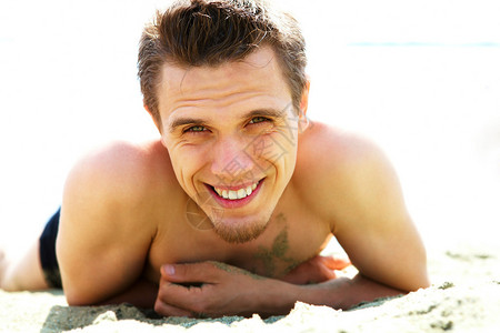 照片中笑着的家伙躺在沙滩上看着照图片