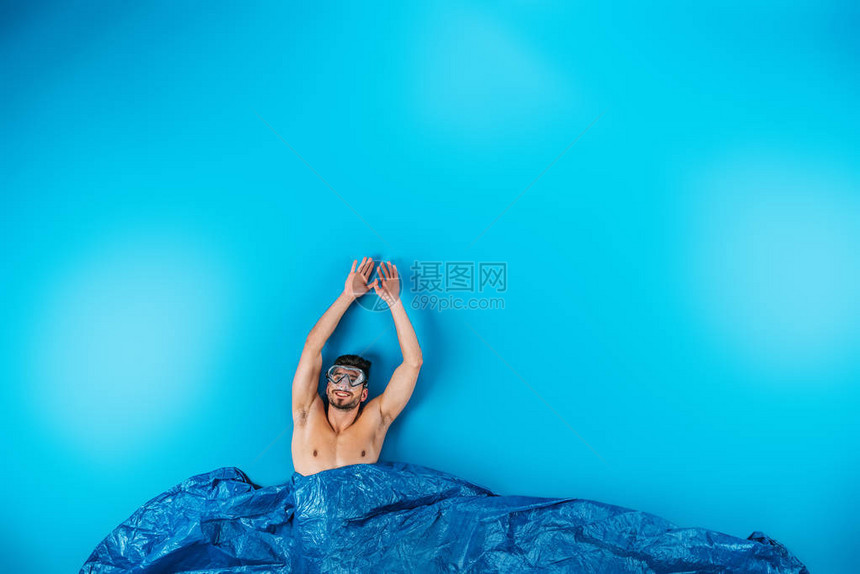 快乐的年轻男子在游泳面具中举起双手从蓝色的想象波图片