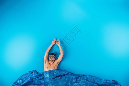 快乐的年轻男子在游泳面具中举起双手从蓝色的想象波图片