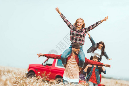 青年妇女骑在男朋友肩上在出车旅行中图片