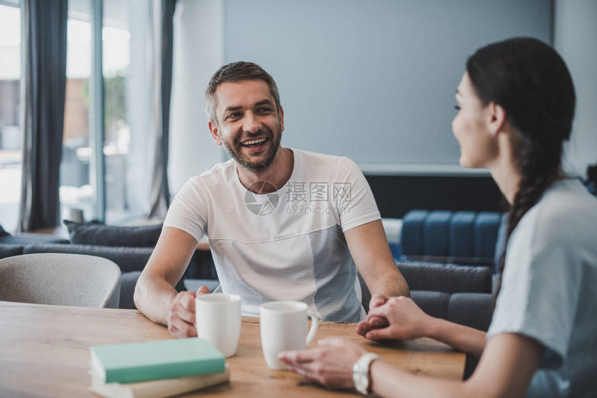 男人在家中用咖啡和书桌边拿着女友的图片
