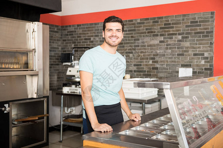 披萨店的年轻服务员站在柜台后图片