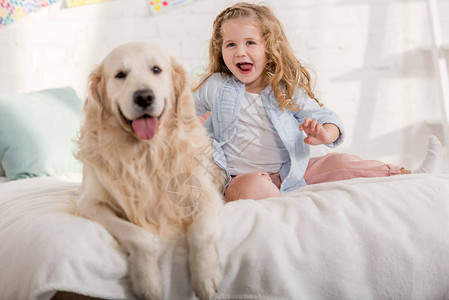 兴奋的可爱孩子和金毛猎犬在儿童房的图片