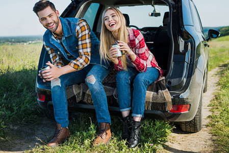 乡村地区两对带着咖啡杯坐在汽车后备箱图片