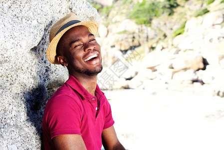 在海滩上笑着的戴着帽子的年轻快乐男孩图片