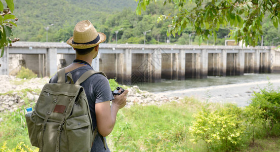 带着背包的亚洲青年旅游男子拿着照相机图片