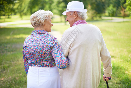 快乐的老年夫妇在公园散步时说背景图片