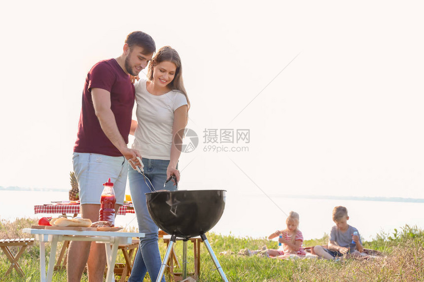 快乐的一对年轻夫妇在户外烧烤炉上图片