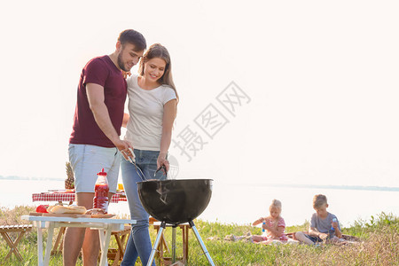 快乐的一对年轻夫妇在户外烧烤炉上图片