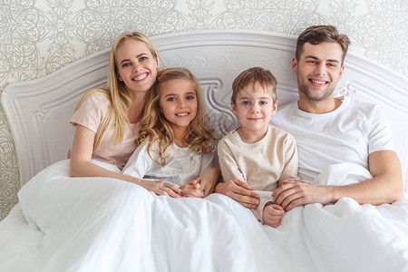 周末早上一起在床上休息的年轻家庭图片