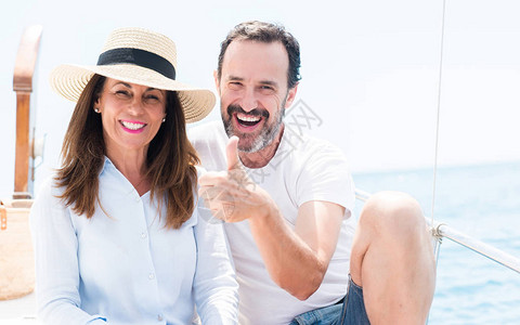 乘坐帆船旅行的中年夫妇开心地笑着做好手势图片